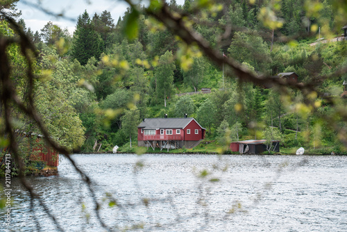 Konstfotografi Red wooden cabin on the shore of a forest lake in Norway