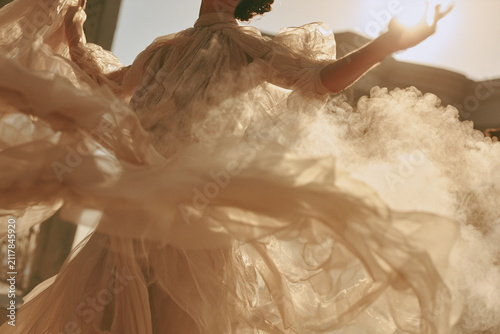 Graceful woman dancing in flowing fabric with golden sunlight and soft mist, elegant luxury fashion concept for beauty, fragrance and lifestyle campaigns.