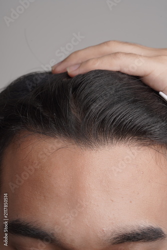 Photography Man styling and inspecting frontal hair roots and hairline on white background