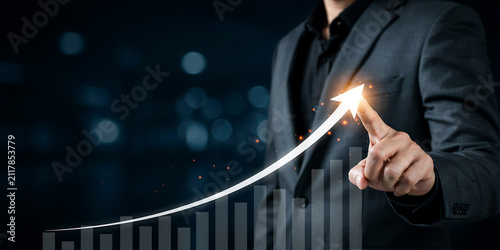 Businessman hand touching virtual glowing arrow rising graph for business growth and financial success with business investment strategy management corporate development marketing planning