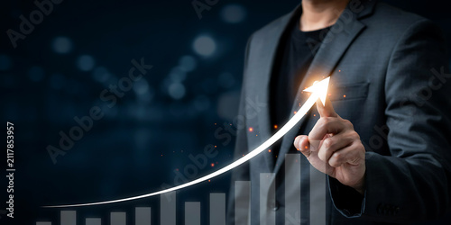 Hand of professional touching glowing upward arrow chart symbolising business development and success with business investment corporate management strategy development analysis marketing