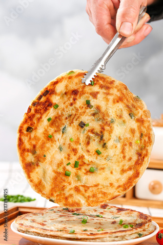 Canvas Print Traditional Scallion Pancake Being Lifted with Tongs - Golden Fried Asian Breakf