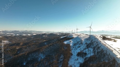 Panoramic aerial view of wind turbines on a snow-covered mountain range