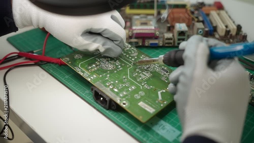 Close-up an electronics technician soldering a printed circuit board during electronic equipment repair. Precision engineering, PCB diagnostics, right to repair. Technology and electronics service.
