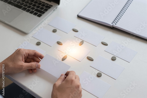 Hands Arranging Blank Business Cards with Geometric Tokens on Office Desk