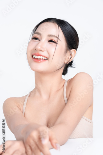 Smiling beautiful young Asian woman with glowing makeup and healthy facial skin, isolated on white background.