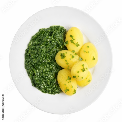 Rahmspinat mit Salzkartoffeln auf weißem Teller, klassisch und schlicht serviert. Studioaufnahme in exakter Vogelperspektive vor weißem Hintergrund, freigestellt und sauber.