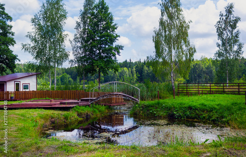 Decorative pedestrian bridge over a small river in the countryside.