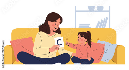 Caring mother teaching her young daughter the alphabet using letter cards while sitting on a cozy yellow sofa.