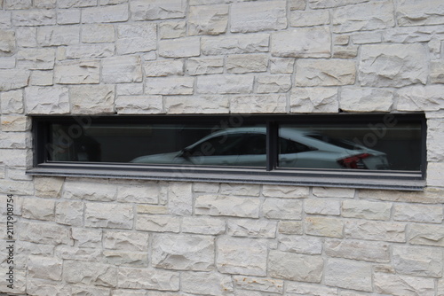 Modern brick wall and facade with window and a car reflection. Outdoor building with window reflection. Modern architecture in city and textured bricks.