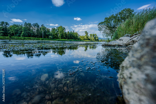 Ein ruhiger Fluss in der Natur mit Wasser, Bäumen und klarem Himmel bei Tageslicht