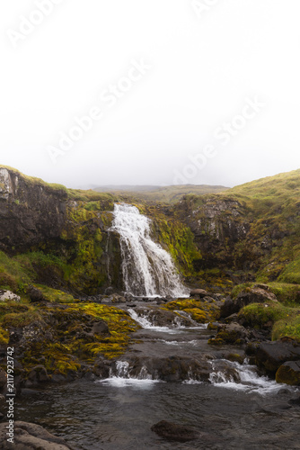 Freshwater cascades over mossy basalt rocks in West Iceland