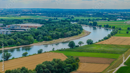 Ein Fluss windet sich durch eine grüne Landschaft mit Feldern und Bäumen in der Nähe einer Stadt