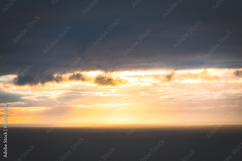 Fototapeta premium Golden sunset illuminates dramatic clouds above calm water in Iceland
