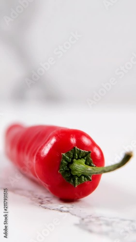 Close up of a single vibrant red chili pepper on a marbled surface