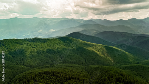 Fotografía An emerald ridgeline curves toward hazy summits under a sky