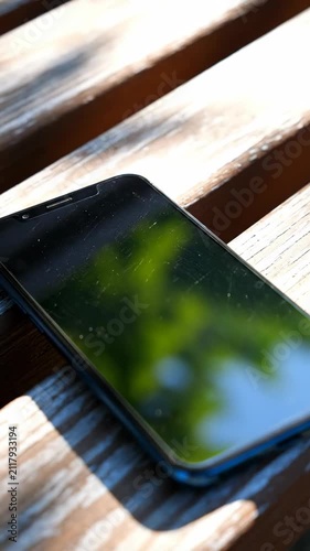 Smartphone on a wooden surface in sunlight