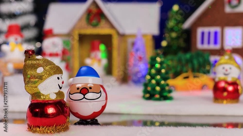 Against the backdrop of a small Christmas village, an unusual Santa Claus comes running to a snowman