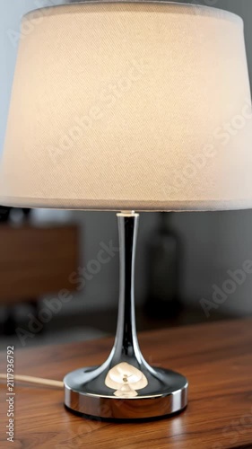 Modern table lamp with polished chrome base on a wooden surface