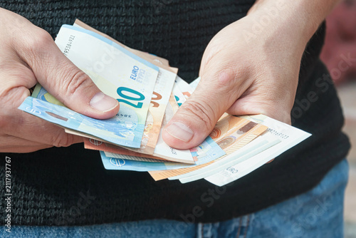 A man counts euro bills, close-up.