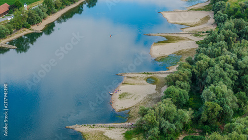 Flusslandschaft mit Sandbänken und Bäumen in der Nähe eines kleinen Dorfes