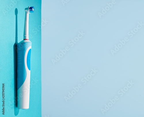 Electric toothbrush on a blue background. Modern technologies for health. Healthy teeth. A modern tool for daily oral care.