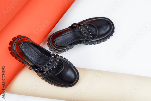 Black women's student shoes. Youth shoes in close-up. A pair of fashionable shoes for teenagers on an orange and white background.