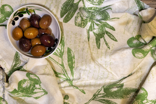 Foto Bowl of mixed olives on linen kitchen towel with copy space, top view