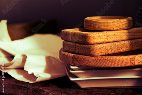 Wooden trays stacked on a table next to ceramic plates in a kitchen setting