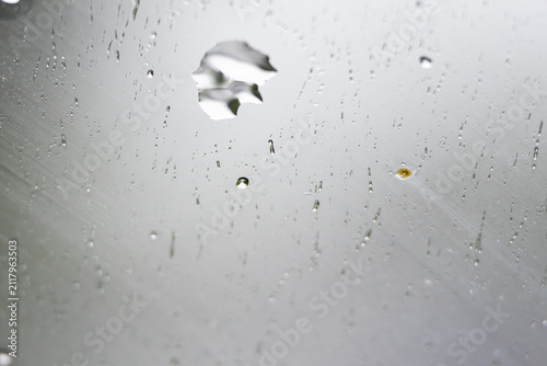 Cuadro en lienzo An irregular droplet silhouette floats among tiny beads on a pale reflective surface