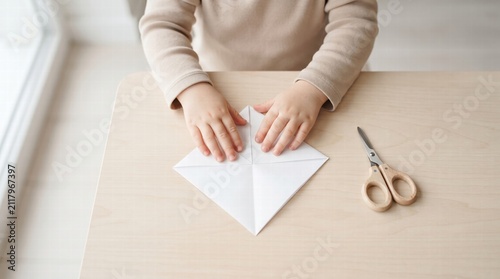 Child Hands Folding White Paper Origami Craft at Wooden Table