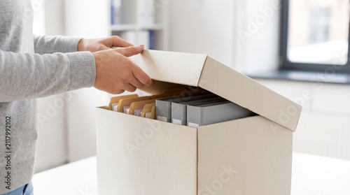 Office worker lifting the lid off a cardboard storage box filled with file folders