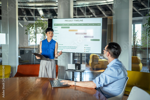Female professional presenting project timeline in modern office meeting