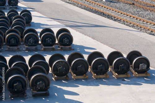 Train wheelsets stored in row outside railway maintenance facility near tracks