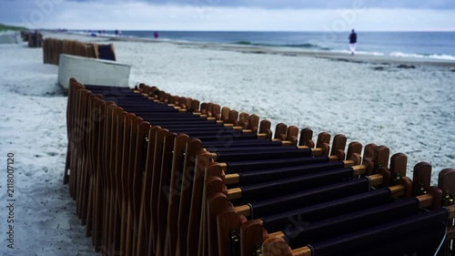 Foldable wooden pathway providing accessibility on a sandy beach. The temporary walkway leads to the sea under a cloudy, overcast sky