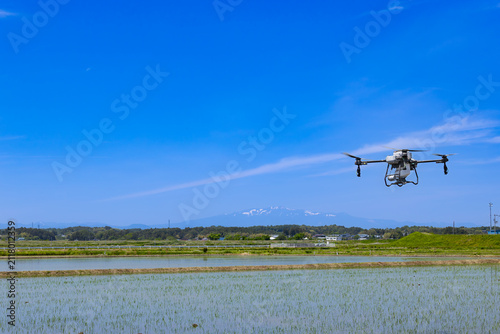 ドローンによる水田への除草剤散布と残雪の栗駒山