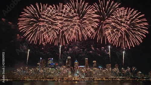 Bright colorful fireworks illuminate the night sky over a city skyline