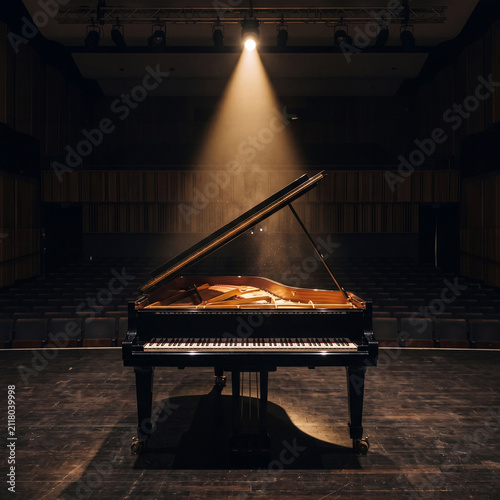 Elegant Grand Piano Standing Alone on Stage Under a Single Dramatic Spotlight in an Empty Dark Concert Hall