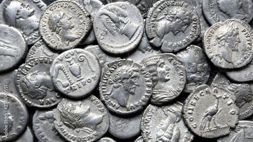 Close-up of ancient Roman silver coins in a money pile. Macro photography of old metallic currency with emperor profiles. History, antique and archaeology background