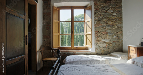 Rustic italian bedroom with stone wall and cypress trees