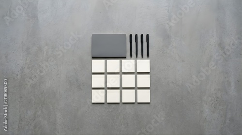 Gray notepad with pens and sticky notes arranged on a concrete background