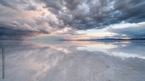 Storm clouds over salt flats. Dramatic sky reflection on a vast mirror-like landscape.