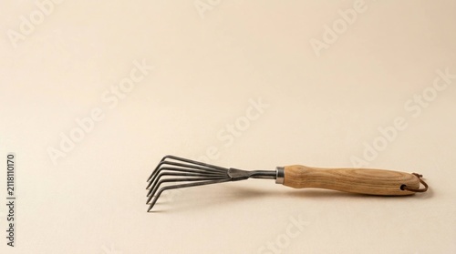 Handheld Garden Rake Tool for Soil Cultivation Isolated on Beige Background