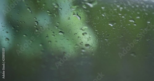 Close up of raindrops on glass with blurry green nature background