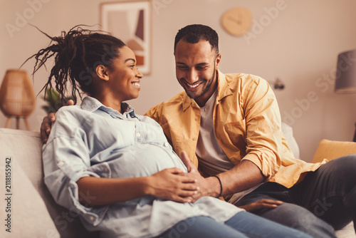 Konstfotografi Joyful Couple, Black Man And Woman, Expecting A Baby Together, Smiling While Sitting On Couch At Home, Enjoying Each Other's Company With Happiness And Anticipation