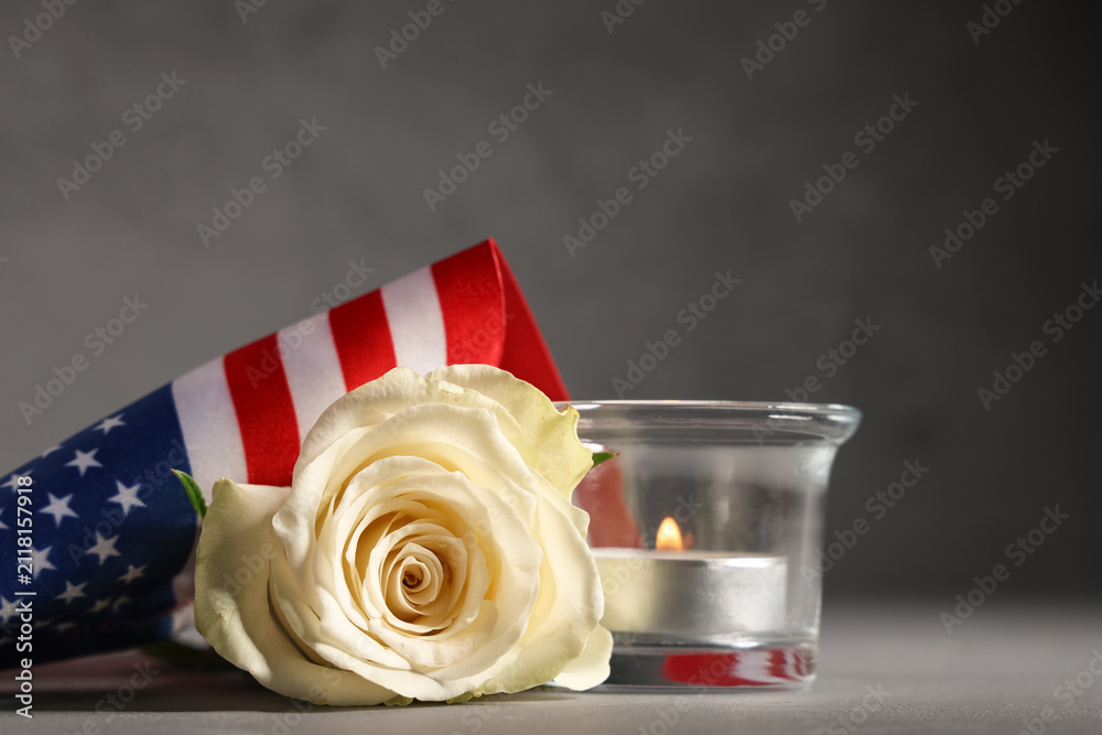 Obraz premium White rose, american flag, and lit candle for memorial day or veterans day remembrance