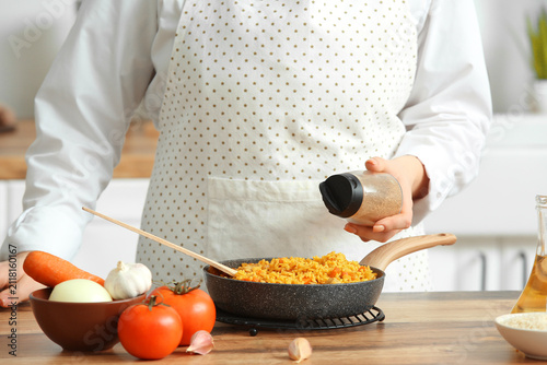 Woman peppering pilaf in fr...