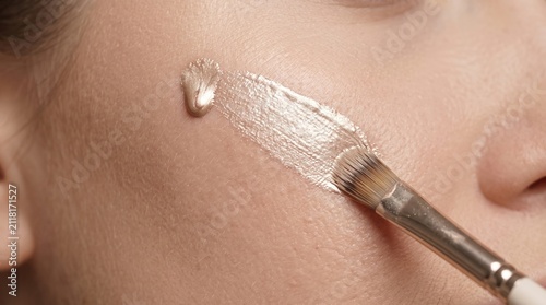 Close Up of Makeup Brush Applying Liquid Highlighter Swatch on Female Cheek