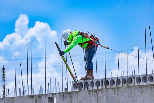 Fotografie Side view of a construction worker using a pry bar to position precast hollow co