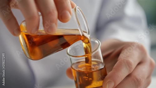 Pouring Herbal Extract into Laboratory Glass Flask for Natural Medicine Preparation